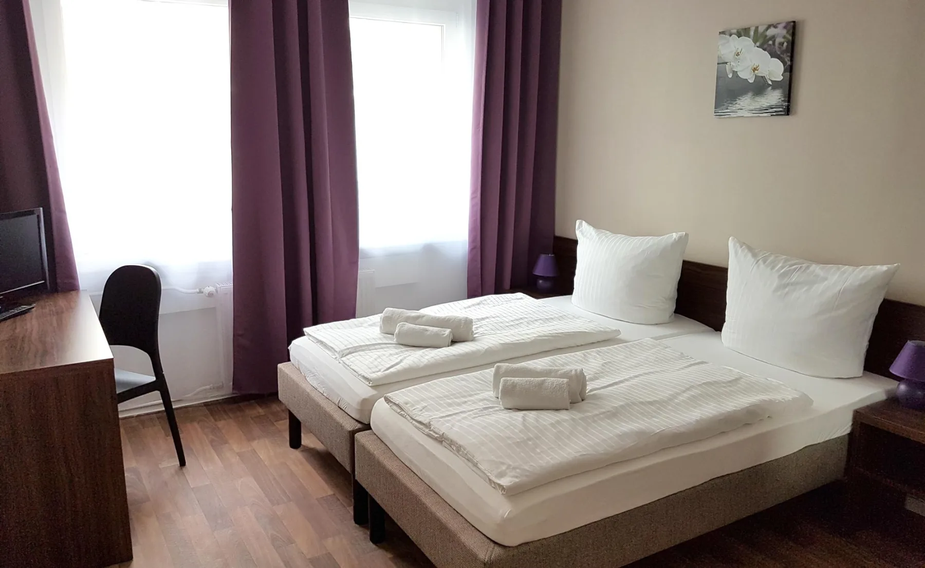 Doppelzimmer mit zwei zusammengestellten Betten und großen Fenstern